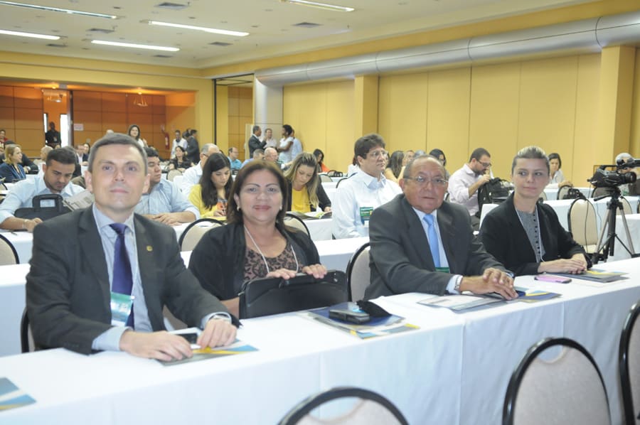 Quatro participantes sentados na primeira fila durante o evento.