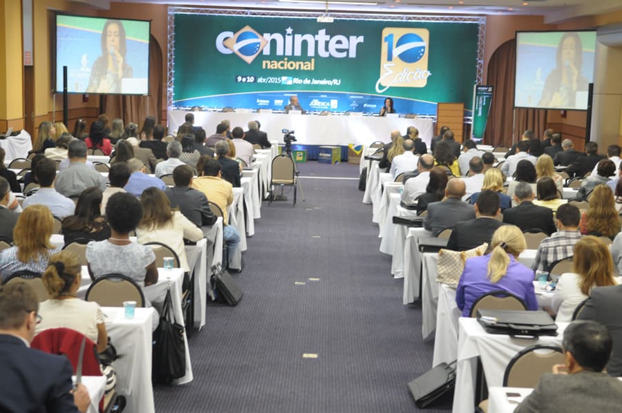 Plateia numerosa acompanha a mesa do congresso, com telões laterais transmitindo quem fala.